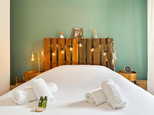 a bedroom with a white bed with towels and lights at Le Cocon - Terrasse & Parking - Calme in La Mézière