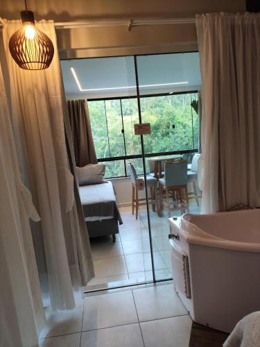 a bathroom with a tub and a bedroom with a table at Bombinhas Guest House in Bombinhas