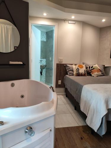 a bathroom with a bed and a tub next to a bed at Bombinhas Guest House in Bombinhas