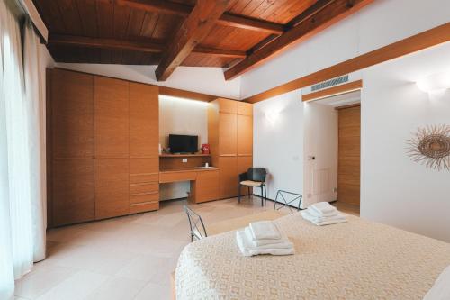 a room with a bed and a desk with a television at Masseria Stali, The Originals Relais in Caprarica di Lecce