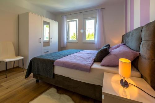 a bedroom with a bed and a table and two windows at Villa Veronika in Omiš