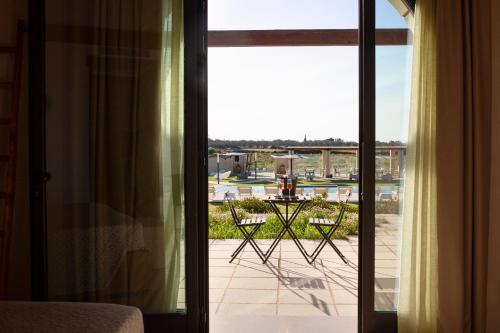 a room with a door open to a patio with a table at Masseria Stali, The Originals Relais in Caprarica di Lecce