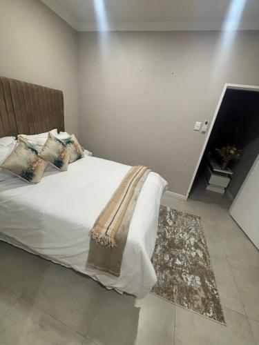a bedroom with a bed with white sheets and a rug at Tranquil Stays in Polokwane