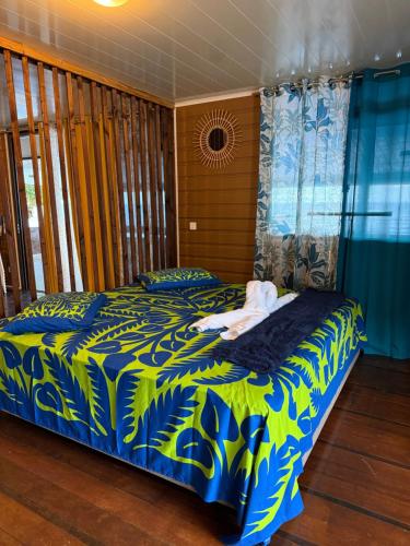a bedroom with a bed with a blue and green blanket at Fare Vaitaua in Faaone