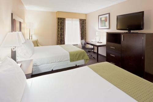 a hotel room with two beds and a flat screen tv at Holiday Inn Express Hotel & Suites Charleston-Southridge by IHG in Charleston