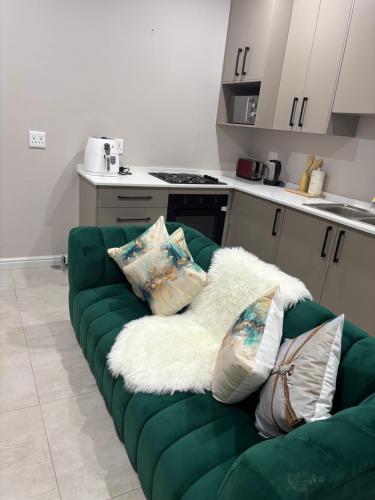 a green couch with pillows on it in a kitchen at Tranquil Stays in Polokwane