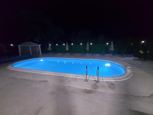 Una gran piscina azul por la noche en Къща за гости Бела, en Targóvishte