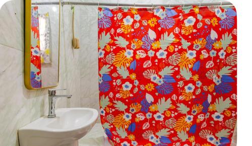 a bathroom with a red shower curtain and a sink at Tamaras Inn in Ocho Rios
