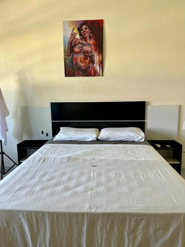 a bed in a bedroom with a painting on the wall at Hostel Londrina in Londrina