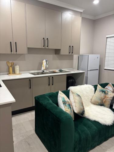 a living room with a green couch in a kitchen at Tranquil Stays in Polokwane