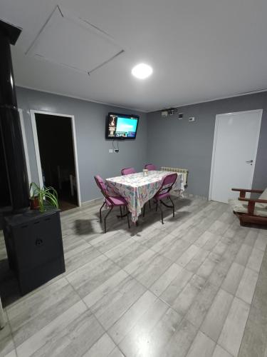 a dining room with a table and chairs and a television at Casa de campo La Genoveva in Río Gallegos