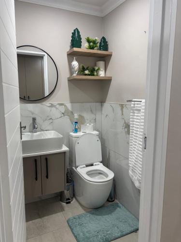 a bathroom with a toilet and a sink and a mirror at Tranquil Stays in Polokwane