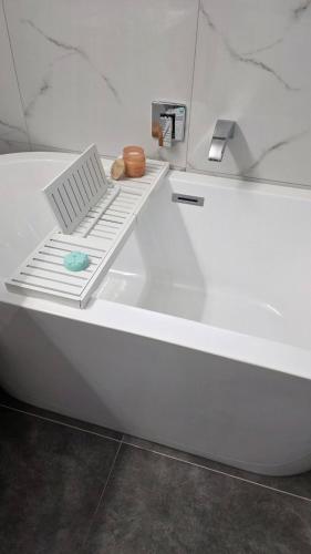 a white bath tub with a shelf on top of it at Northshore Central Cosy & Comfortable 3BR Home in Auckland