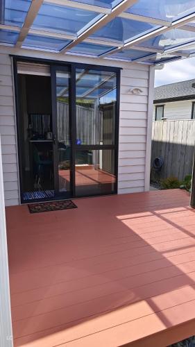 a patio with glass doors and a deck at Private Modern 2 bedroom Unit in Central Albany in Auckland