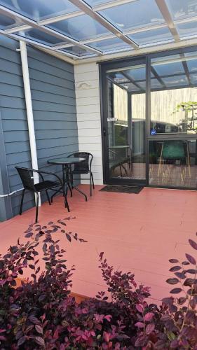 a patio with two chairs and a table and windows at Private Modern 2 bedroom Unit in Central Albany in Auckland