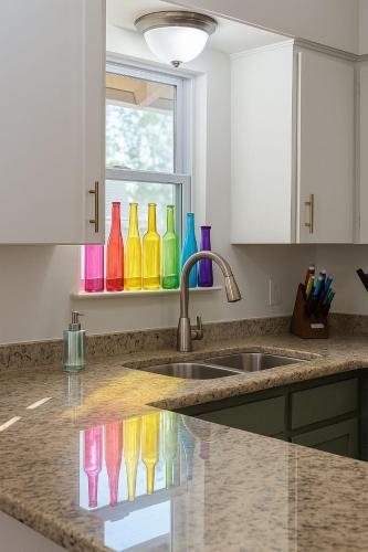 a kitchen counter with colorful glass vases on a window at SoCo Greenery Home for Long Stays with Spacious Fenced Yard & Ameniites in Austin