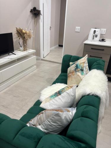 a green couch with pillows in a living room at Tranquil Stays in Polokwane