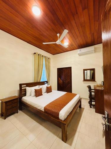 a bedroom with a bed with a wooden ceiling at Ayana Beach Garden in Negombo