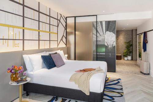a bedroom with a large white bed and a table at Hotel Indigo Melbourne Little Collins in Melbourne