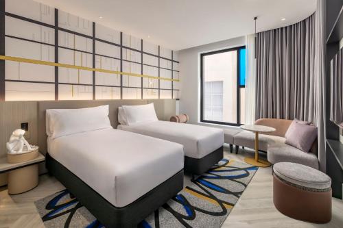 a hotel room with two beds and a couch at Hotel Indigo Melbourne Little Collins in Melbourne