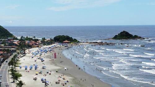 a beach with a lot of people and the ocean at Frente para Mar de água cristalinas in Itanhaém