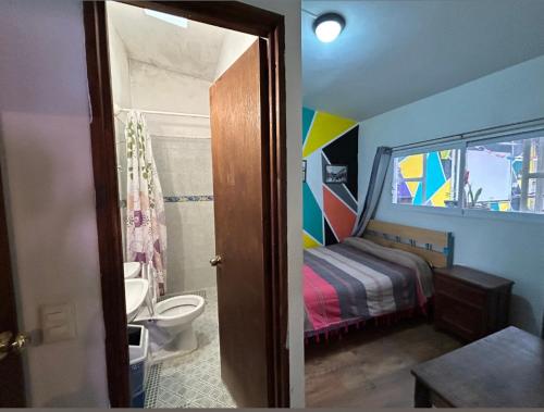 a bathroom with a bedroom with a bed and a toilet at Hostel Casa De Yagil in San Cristóbal de Las Casas