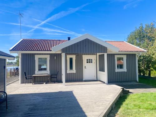 a small grey shed with a table and chairs on a deck at Seaside Home with Stunning Views Overlooking Blekinge Archipelago in Ronneby