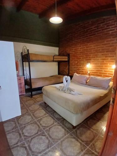 a bedroom with two beds and a brick wall at La Casa de La Linda in Salta