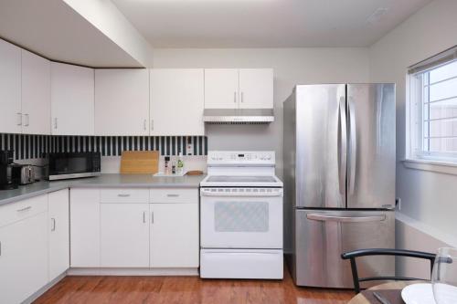a kitchen with white cabinets and a stainless steel refrigerator at Charming 1 br Retreat in South Surrey White Rock in Surrey