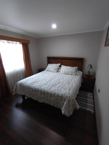 a bedroom with a bed with a white comforter and a window at Visok B&B in Frutillar