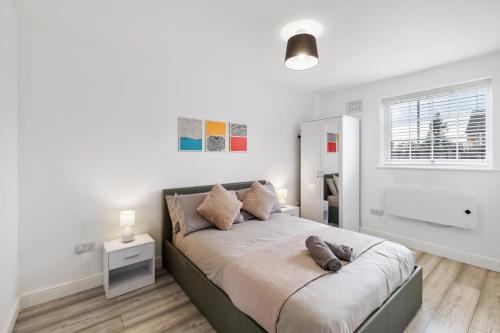 a white bedroom with a bed with pillows on it at Stylish 1 Bed Apt 4 Min to Airport WiFi & Parking in Luton
