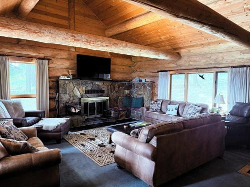 a living room with couches and a fireplace in a cabin at Living Well Lodge with Panoramic Views in Moyie Springs