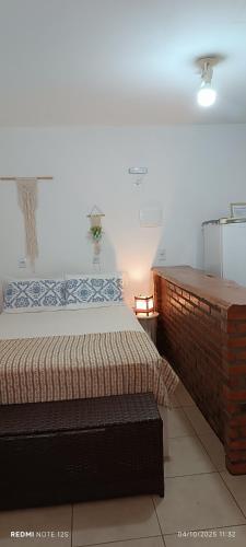 a bedroom with a bed and a brick wall at Studio Baleia Franca in Imbituba