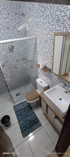 a bathroom with a toilet and a sink and a mirror at Studio Baleia Franca in Imbituba