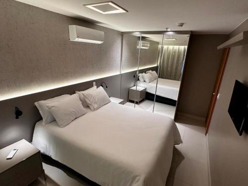 ein Schlafzimmer mit einem großen weißen Bett und einem Spiegel in der Unterkunft Condominio Brisas do Lago in Brasilia
