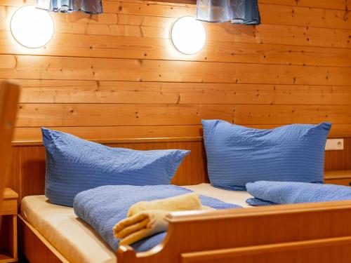 two beds with blue pillows in a room with wooden walls at Haus Joachim in Winkle