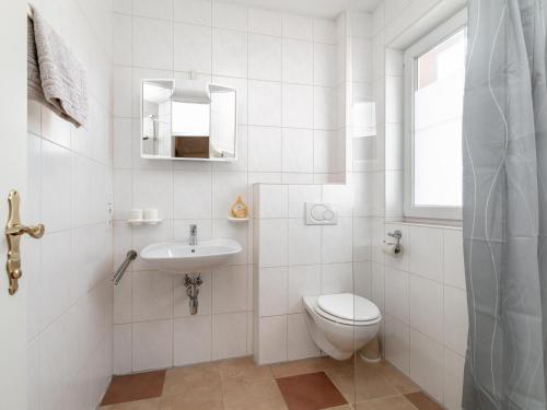 a white bathroom with a toilet and a sink at Haus Oliver 1 in Winkle