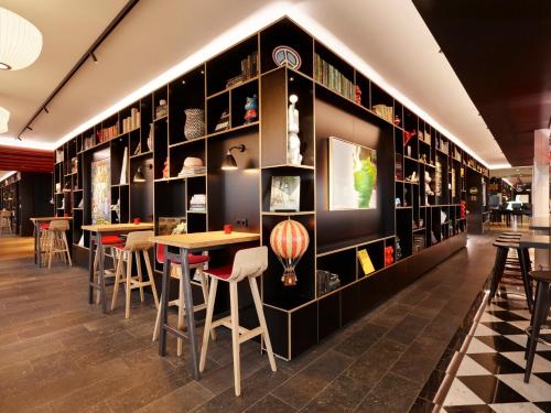 a restaurant with tables and shelves of books at citizenM Copenhagen Radhuspladsen in Copenhagen