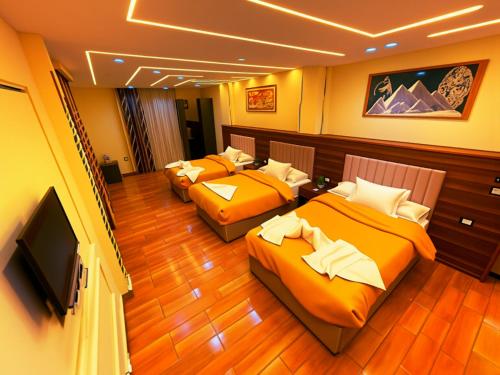 a room with three beds and a flat screen tv at GOLDEN PYRAMiDS TEMPLE ViEW HOTEL all king rooms with jacuzzi & pyramids view in Cairo