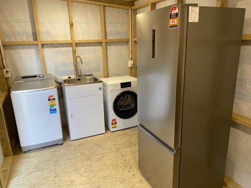 a laundry room with a refrigerator and a washing machine at Whakaipo Bay Cabin Retreat Taupo in Taupo