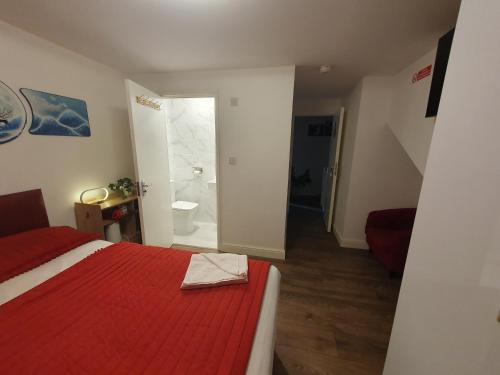 a bedroom with a red bed and a bathroom at AMH Hotel - Greenford Station in Northolt