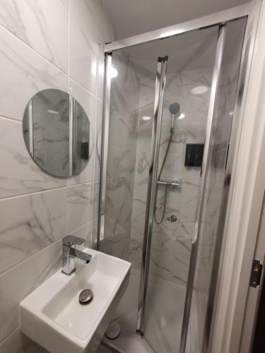 a white bathroom with a sink and a shower at AMH Hotel - Greenford Station in Northolt