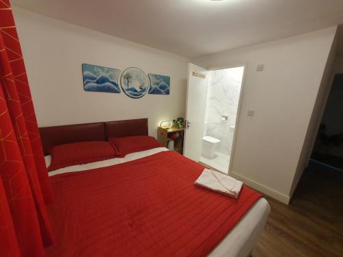 a bedroom with a red bed and a shower at AMH Hotel - Greenford Station in Northolt
