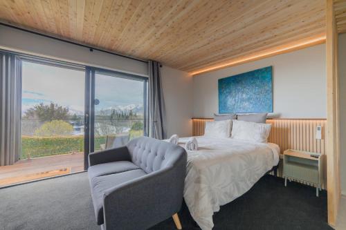 a bedroom with a bed and a chair and a window at Benmore Hideaway Cozy Room with Mini Kitchenette in Lake Tekapo