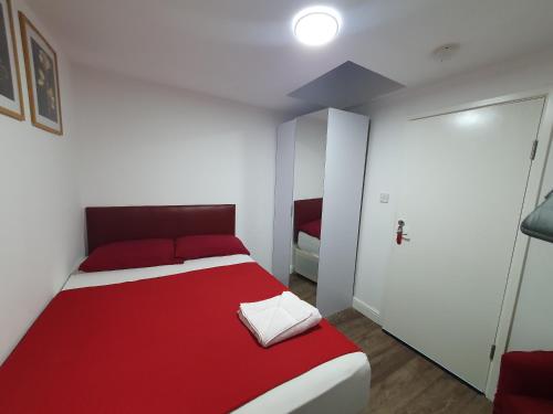 a bedroom with a red and white bed and a door at AMH Hotel - Greenford Station in Northolt