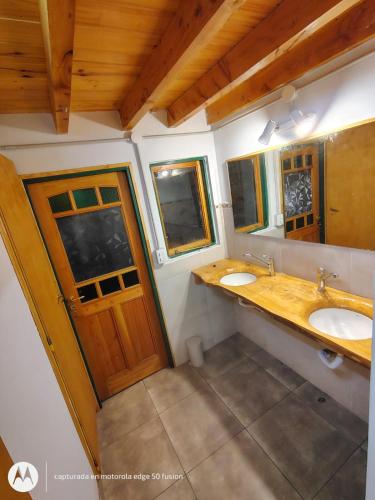 a bathroom with two sinks and two windows at ChacraKremen in El Bolsón