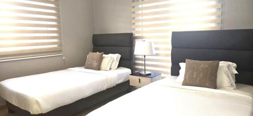 a bedroom with two beds and a lamp and windows at THE POOL LABONE in Accra