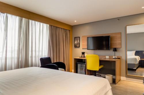 a hotel room with a bed and a desk and a tv at Holiday Inn Sao Paulo Parque Anhembi by IHG in Sao Paulo