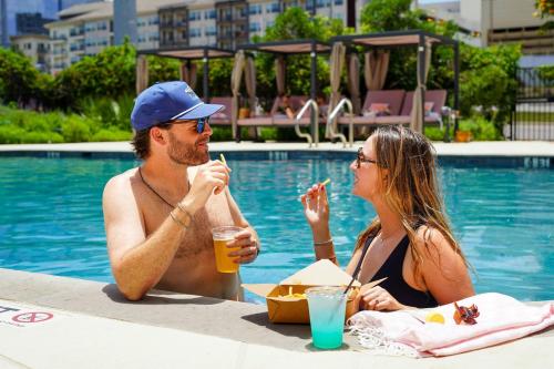 a man and a woman eating food next to a pool at The Westin Austin at The Domain in Austin