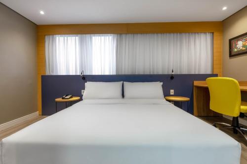 a bedroom with a large bed and a yellow chair at Holiday Inn Sao Paulo Parque Anhembi by IHG in Sao Paulo